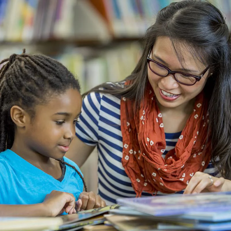 Teacher working with student in library